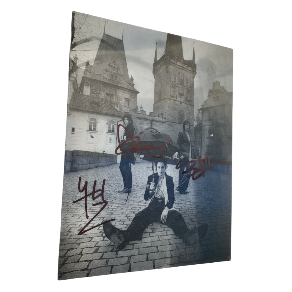 Framed black and white photo of a person sitting on a cobblestone street with a tower in the background