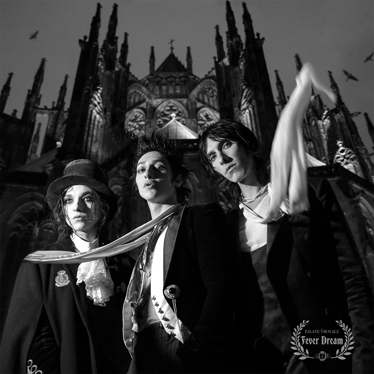 Three people in formal attire standing in front of a cathedral with 'Fever Dream' branding.