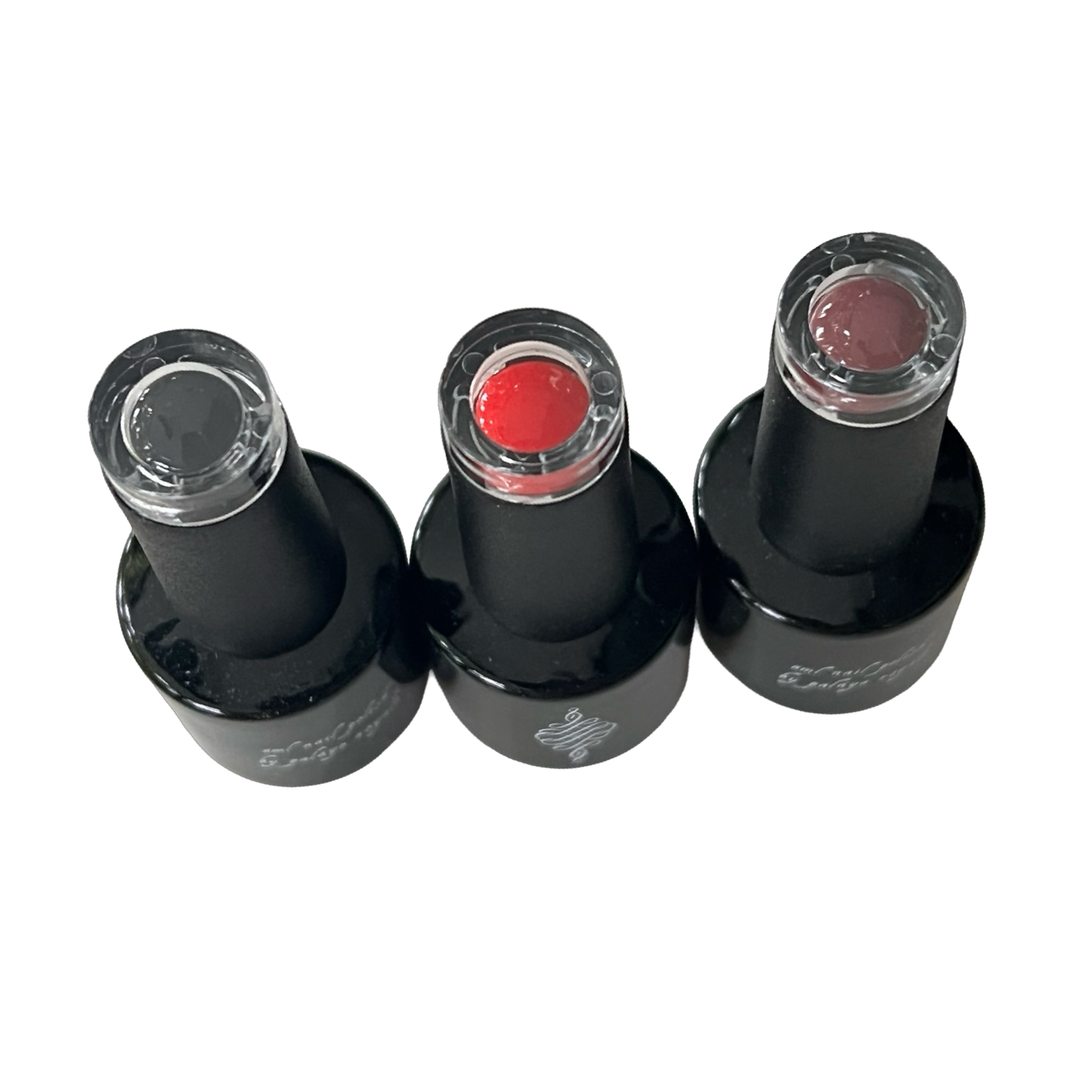 Three black nail polish bottles with different colored polishes on a white background