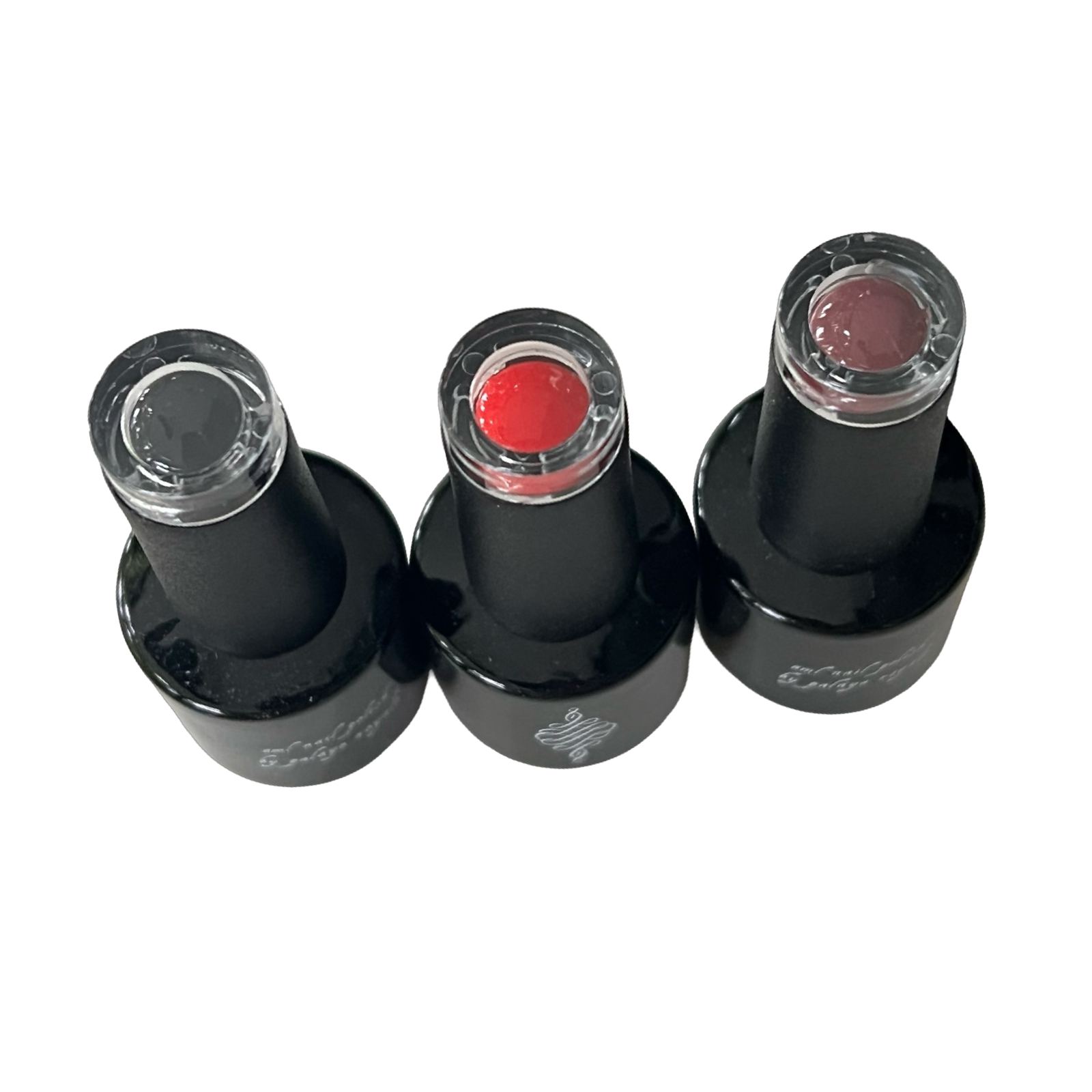 Three black nail polish bottles with different colored polishes on a white background